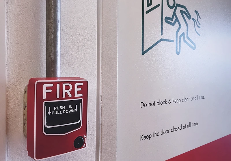 An image of a fire alarm next to emergency exit instructions